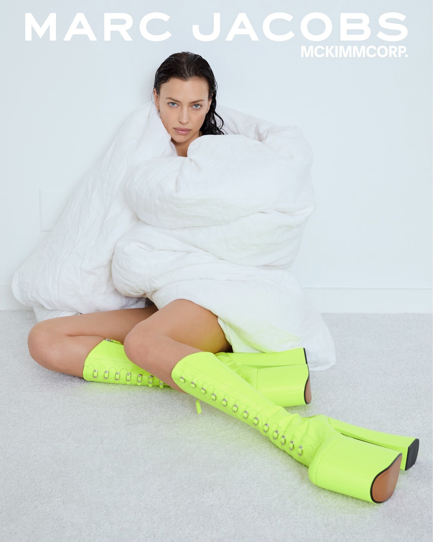 Прикрывшись подушкой, Ирина Шейк без белья рекламирует обувь кислотных цветов